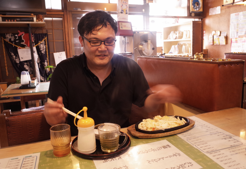 A man with a beaming smile, savoring 'Yutaka Udon' after a long while in Minami-ku, Nagoya.