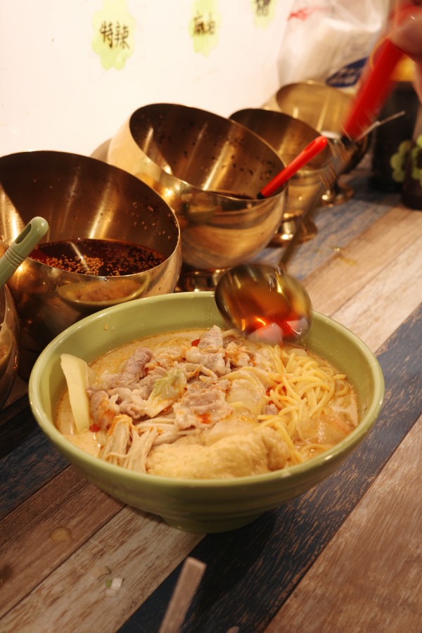 Enhancing the Chinese food experience in Nagoya at Zhang Chuang Malatang with customizing noodles using vinegar and chili oil.