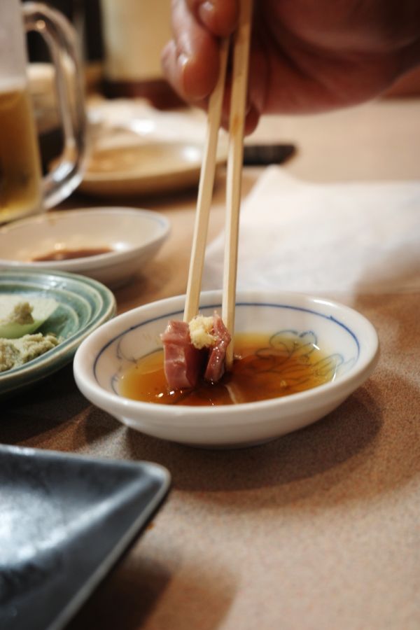 Fresh chicken sashimi being dipped into oil at Daiyasu in Nagoya