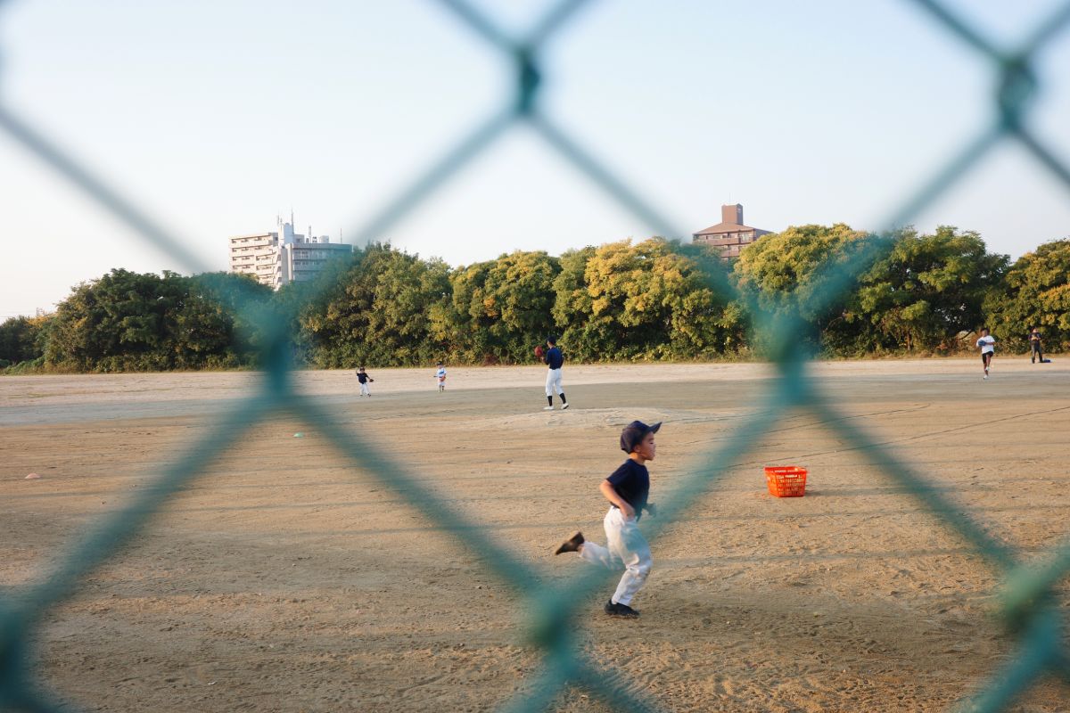 Young kids running and playing on the baseball field at Daikou Park by the Yada River, Higashi-ku, Nagoya, on a sunny day.