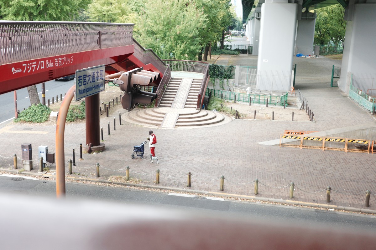 Man strolling with dog through the scenic paths of Wakamiya Odori Park in Nagoya.