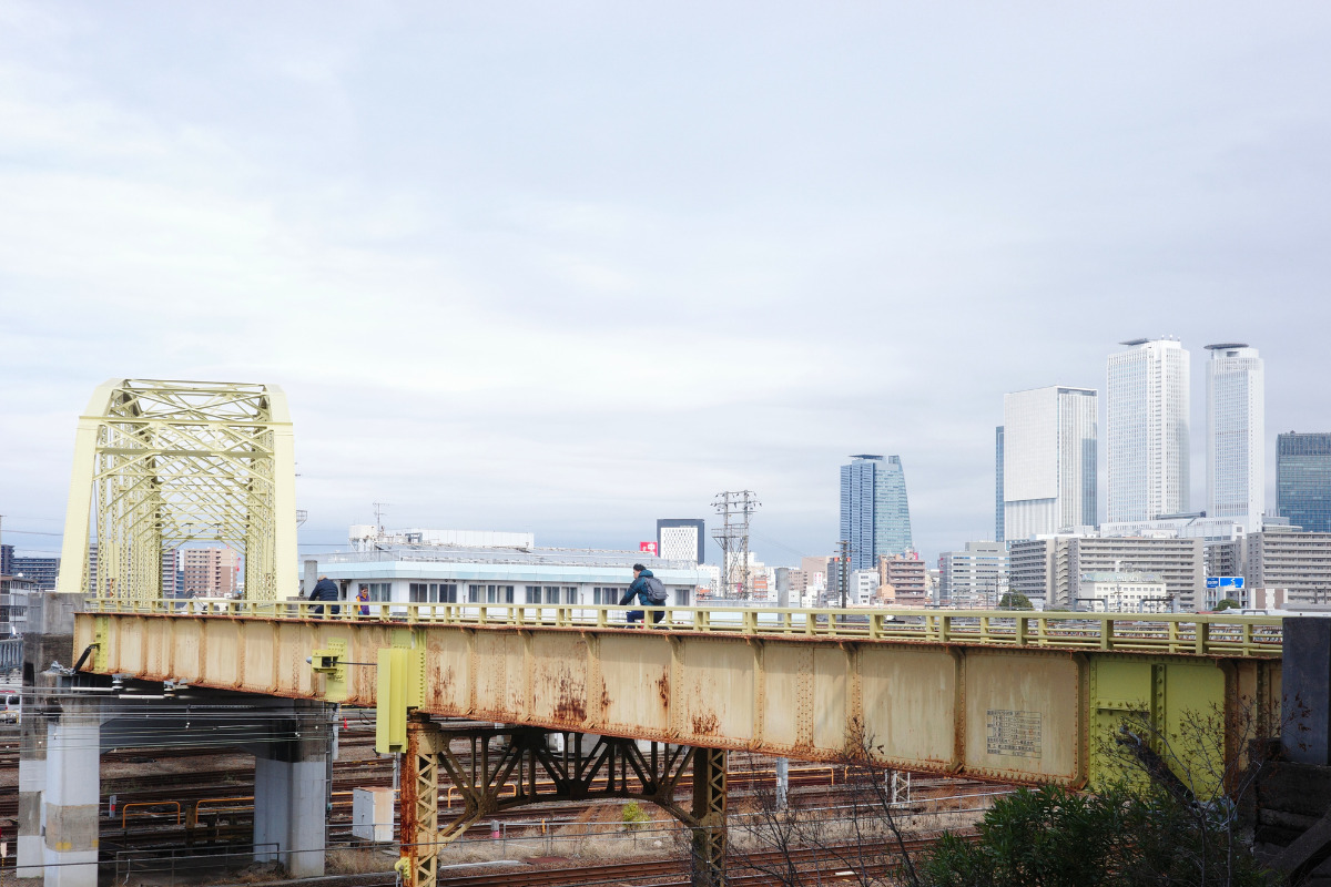 Pedestrians crossing the overpass at Kouya Bridge, a hidden gem in Nagoya, with a view of the cityscape.