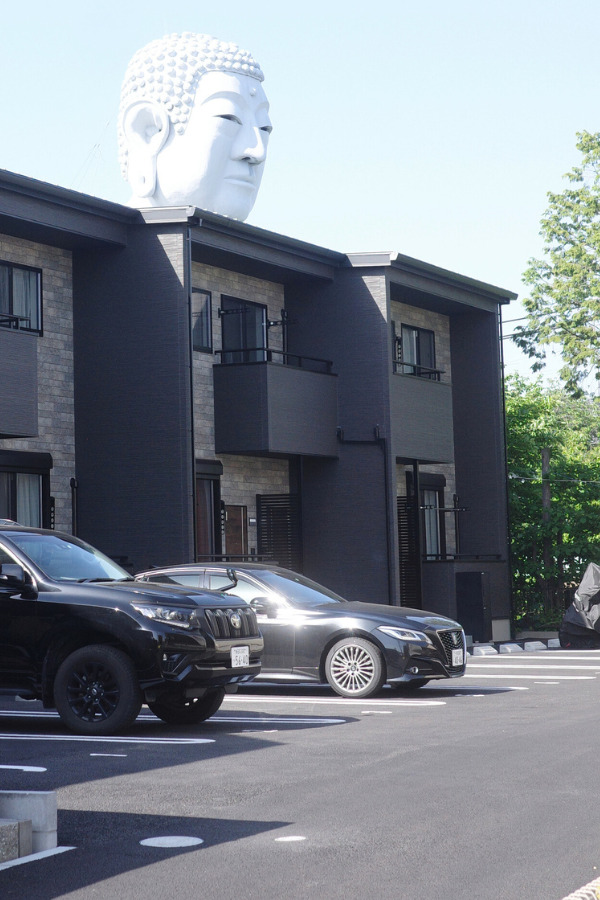 The Great Buddha at Hotei, with its head visible above a modern apartment building.