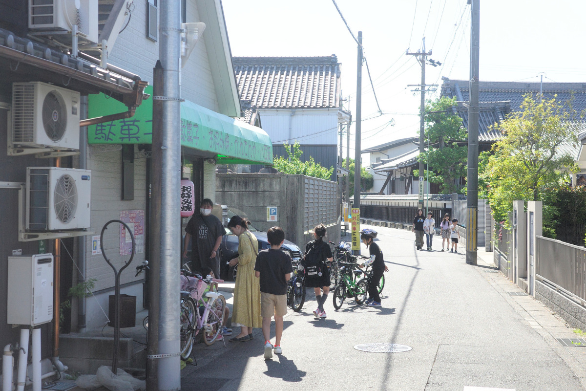 A bustling scene outside Kantenya, a traditional dagashi-ya in Nagoya, highlighting Nagoya's local food and culture as children and families gather.