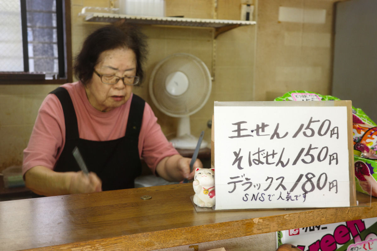 The elderly owner at Kantenya, a dagashi-ya, highlighting Nagoya's local food and culture.