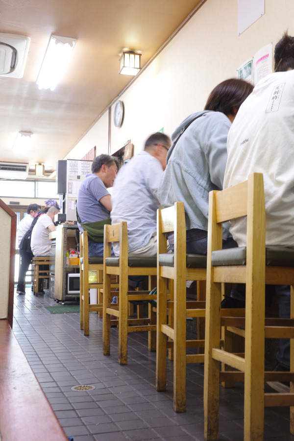 A cozy, nostalgic interior of Chomei Udon with customers enjoying their meals, representing beloved local udon in Nagoya. 