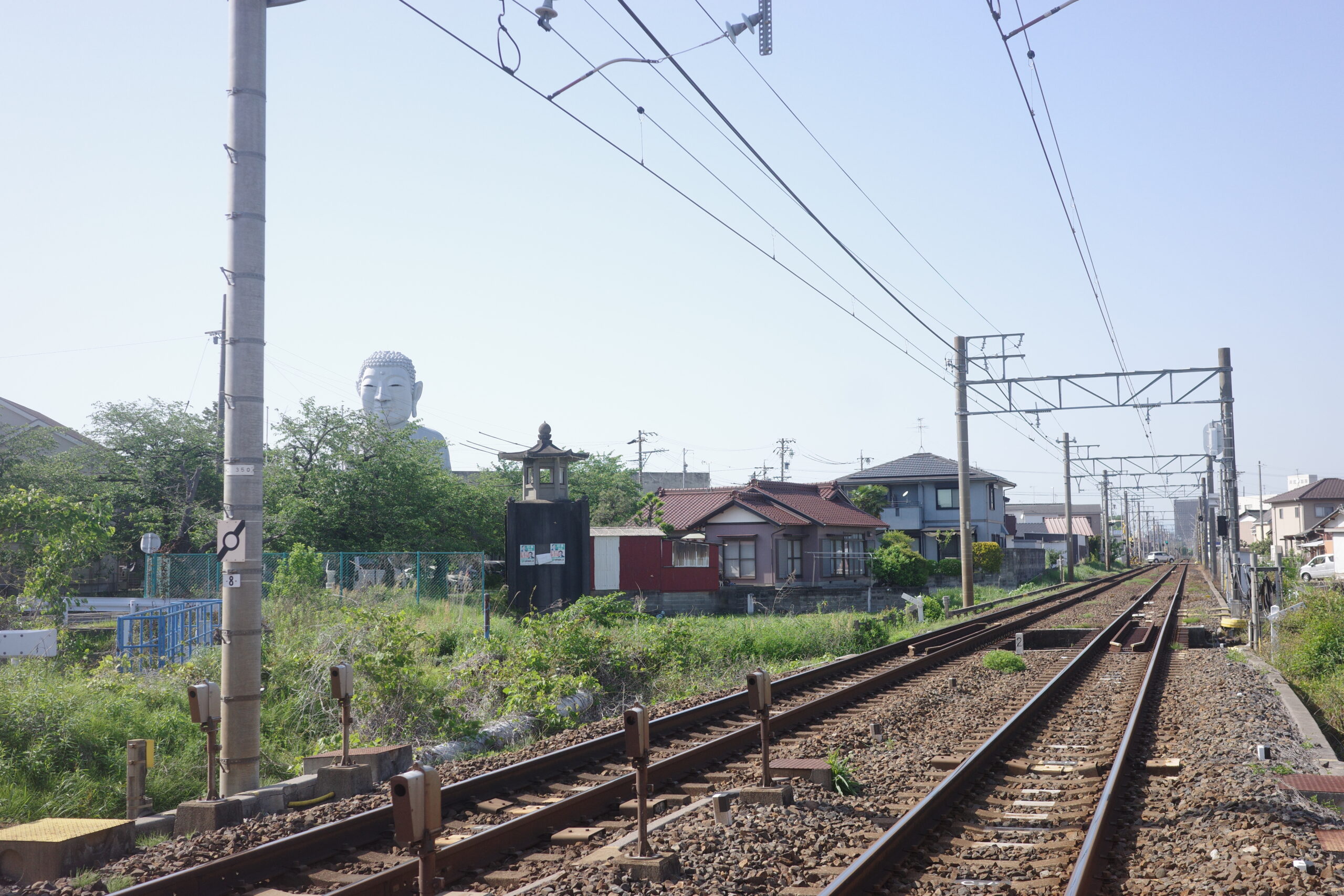 The Great Buddha at Hotei seen from the railway tracks, adding to the unique atmosphere of the area.