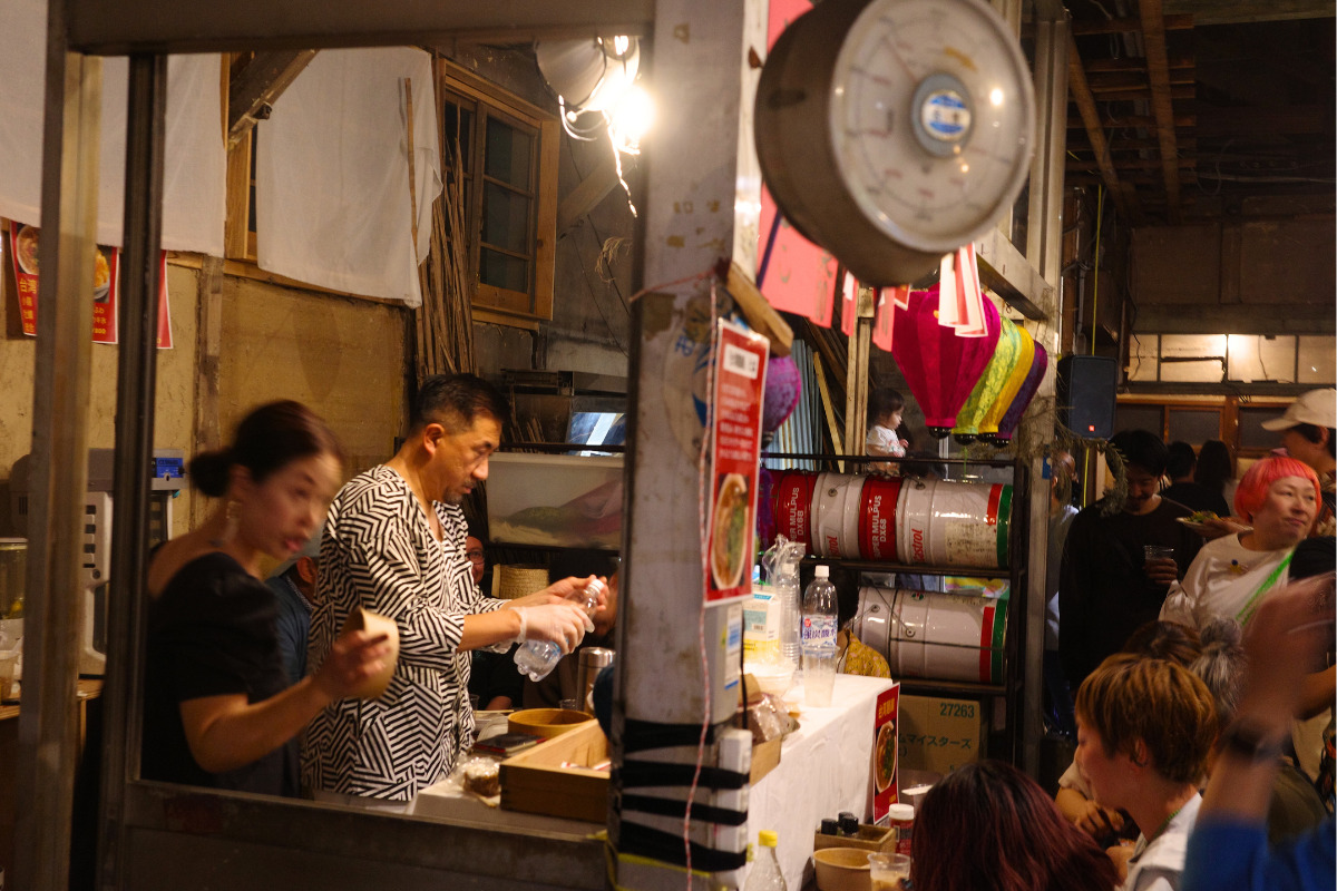 A vendor serving drinks at a stall in Kinjo Market.