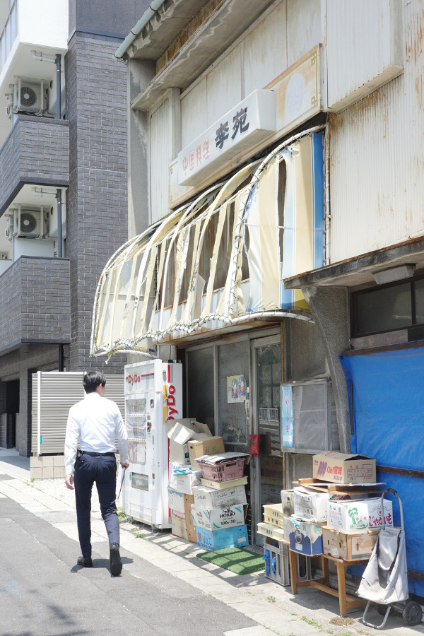 A patron approaching the entrance of Rien (李苑) , a hidden gem in Nagoya. The worn-out awning and rustic exterior belie the flavorful dishes awaiting inside