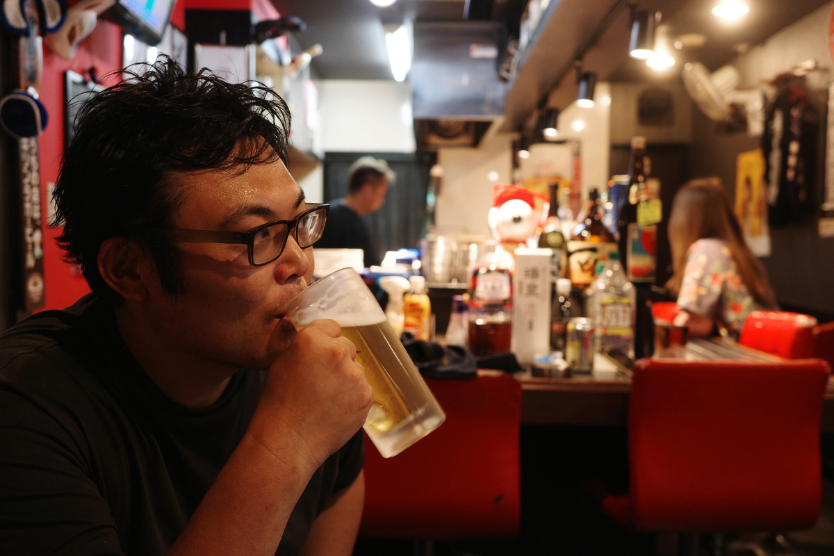 A man having a cold draft beer at Konchan Nagoya's hidden gem teppanyaki izakaya.